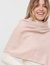 Bufandón tejido de poliéster, color rosa pálido con textura jaspeada en tonos pastel (naranja, lila, gris). Presenta un tejido grueso y flecos en los bordes.