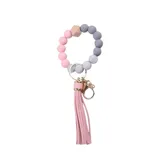 Llavero con pulsera de cuentas de silicona en tonos rosa, gris y madera, con dije de borla rosa y herrajes dorados.