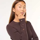 Vestido largo de tejido de punto acanalado color marrón oscuro, de manga larga y cuello redondo. Presenta una abertura lateral en la falda.