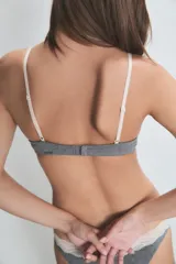 Conjunto de ropa interior color crema, compuesto por un corpiño triangular de algodón con encaje en el escote y una bombacha tipo bikini con encaje en la cintura.