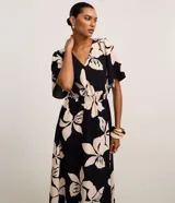 Vestido evasé midi de airflow negro con estampado de flores color crema, escote en V, sisa alargada, mangas cortas amplias y lastex en la cintura.