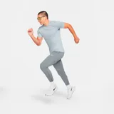 Pantalón largo deportivo Nike Challenger Knit para hombre, color gris con logo blanco en el muslo izquierdo. Corte ajustado con cintura elástica y cordón ajustable. Cuenta con bolsillos laterales y cierres en los tobillos.