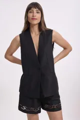 Short negro de cuero sintético con cintura alta, corte holgado y detalle de bordado calado con pequeñas perlas en el ruedo.