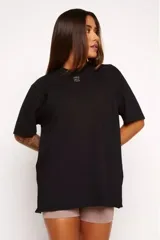 Remera negra de algodón sustentable, corte oversized, con cuello redondo y mangas cortas. Estampado frontal pequeño con la frase "pace your race".