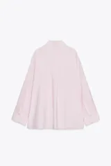 Camisa rosa claro confeccionada en hilatura con modal, de corte holgado, con cuello solapa, manga larga terminada en puño, dos bolsillos con solapa en el delantero y cierre frontal con botones.