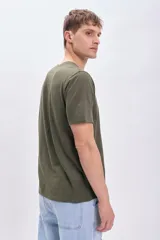 Remera verde militar de manga corta con estampa frontal blanca con la palabra 'Surface' y la frase 'Beyond Reflections'.