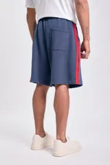 Short deportivo de tela de algodón, color azul marino, con franjas laterales rojas. Tiene cintura elástica y corte holgado.