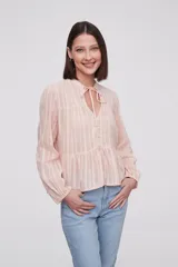 Blusa color rosa pálido con rayas verticales, cuello mao con lazo, mangas largas con puños elásticos, cierre frontal con botones y corte con volantes en la cintura.