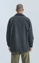 Chaqueta gris de paño con cuello clásico, cierre frontal con botones a presión, bolsillos frontales y corte recto.