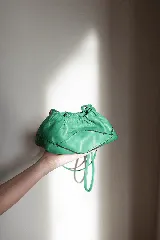 Cartera sobre azul de cuero con frunces y pespuntes diagonales.