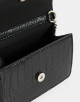 Bandolera negra de cuerina con textura croco, solapa con broche a presión y correa de cadena metálica plateada con charm lateral.