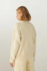 Sweater de lana color crudo, tejido de punto industrial con cuello medio.