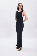 Vestido largo de punto negro con cuello redondo y sin mangas. Tiene corte recto y aberturas laterales en el ruedo.