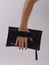 Sobre de mano color crema, con cierre de cremallera y tira de cuero para sujetar a la muñeca.