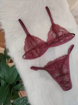 Conjunto de lencería de encaje color bordó, compuesto por un corpiño triangular sin aro y una bombacha less con tiras finas.