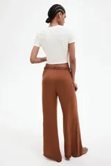 Pantalón palazzo color marrón con cintura elástica y cordón ajustable con cuentas decorativas. Tiene bolsillos laterales discretos.
