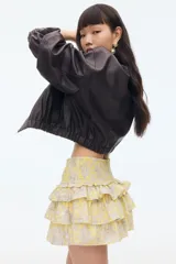 Minifalda amarilla con estampado paisley en tonos grises y cintura elastizada. Presenta volados en capas.