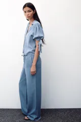 Pantalón celeste de tiro alto con cintura elástica ajustable con cordones, bolsillos delanteros y traseros, y pernera ancha.