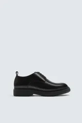 Zapato de vestir estilo derby, color negro, con capellada de cuero, horma redonda y suela de goma con volumen.