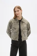 Chaqueta corta de jean con estampado animal print en tonos beige y gris, cuello camisero, cierre frontal con cremallera, bolsillos de parche en el pecho y corte entallado.