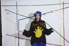 Sweater tejido a crochet a mano 100% en lana, de calce holgado con cuello a la base y puños. Diseño con dibujo de piña y texto 'Ira Fruta'.