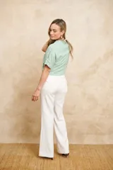 Chaqueta bomber color verde agua, con cierre frontal dorado, bolsillos grandes con cierre y mangas cortas con ajuste mediante lazos.