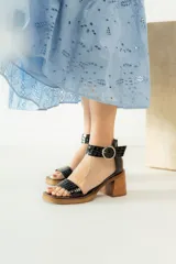 Sandalias de cuero color crudo, con tira ancha sobre los dedos, pulsera con hebilla al tobillo y taco cuadrado de madera.