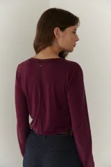 Remera blanca de mangas largas con escote en V y costuras decorativas en negro.