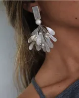 Aros colgantes plateados con forma de hojas y perlas.