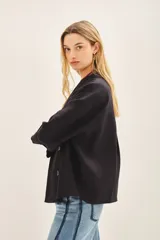 Saco corto de lino negro, de corte oversize con mangas amplias y cruce frontal con doble abotonadura.