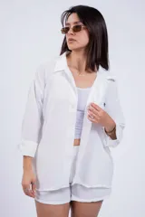 Camisa negra de corte amplio, con cuello clásico, cierre frontal con botones, manga larga con puños arremangados y bolsillo de parche en el pecho.