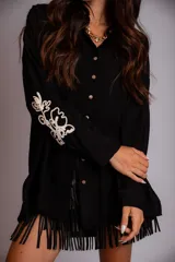 Camisa celeste de corte clásico, con botones frontales y bordados florales en las mangas.