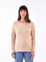 Remera manga larga color beige con cuello redondo y detalle de botones dorados en el hombro.