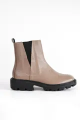 Bota corta de cuero color visón, con elásticos laterales negros, punta redondeada y suela track negra.