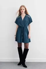 Minivestido negro de escote cruzado, mangas cortas y cintura elastizada con lazo. Presenta cadenitas metálicas en los hombros y en los extremos del lazo.