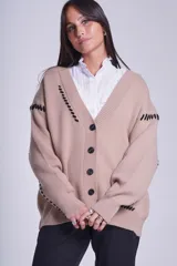 Cárdigan color beige con botones negros, escote en V y detalles de costuras bordadas en negro.