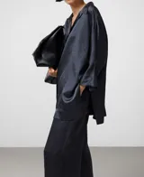 Camisa oversize de mujer, color gris oscuro, confeccionada en acetato 100% con efecto arrugado y brillo natural. Presenta cuello italiano y manga japonesa con puño ancho.
