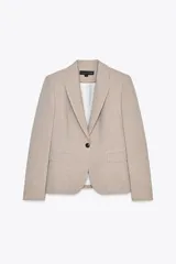 Blazer color beige de corte entallado, con cuello solapa y mangas largas. Tiene bolsillos con solapa en la parte delantera y cierre cruzado con botones.