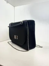 Cartera bandolera negra de cuero sintético con cierre de broche metálico plateado y correa de cadena plateada.