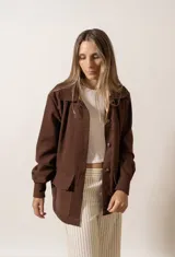 Chaqueta marrón con cuello camisero, cierre frontal con botones, mangas largas y bolsillos de parche en el pecho.