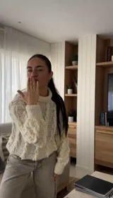 Sweater color crudo de lana merino con cuello alto y un solo hombro al descubierto, tejido a mano.