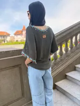 Remera tejida color marrón con hilado 100% algodón y cintas de piedras aplicadas en cuello y mangas.