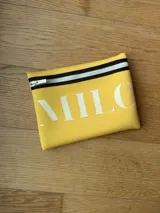 Clutch o neceser negro de neopreno con cierre de cremallera blanco y logo grande en blanco con tipografía serif.