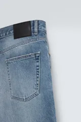 Pantalón de jean negro con corte flare y estilo baggy, con cinco bolsillos, efecto lavado y cierre frontal con botones.