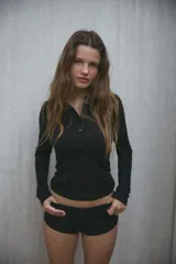 Camiseta negra de manga larga con cuello redondo y cierre frontal con botones.