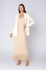 Vestido largo color beige con textura geométrica, breteles finos y escote con nudo. Posee flecos en el ruedo.
