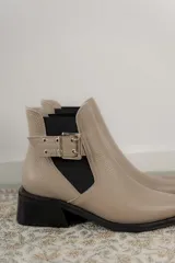 Botines Chelsea color beige con elásticos laterales negros, punta cuadrada, detalle de hebilla lateral y tacón bloque bajo.