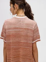 Vestido corto tejido a rayas horizontales en tonos marrones y beige, con cuello redondo y mangas cortas con ribete blanco. Corte recto y holgado.