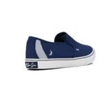 Zapatilla tipo slip-on de lona color azul marino, con suela de goma blanca y detalles en gris. Presenta un logo de velero en el talón y un detalle de costura ondulada en el empeine.