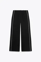 Pantalón negro capri de tiro alto con bolsillos delanteros, cintura elástica y banda lateral blanca a contraste.